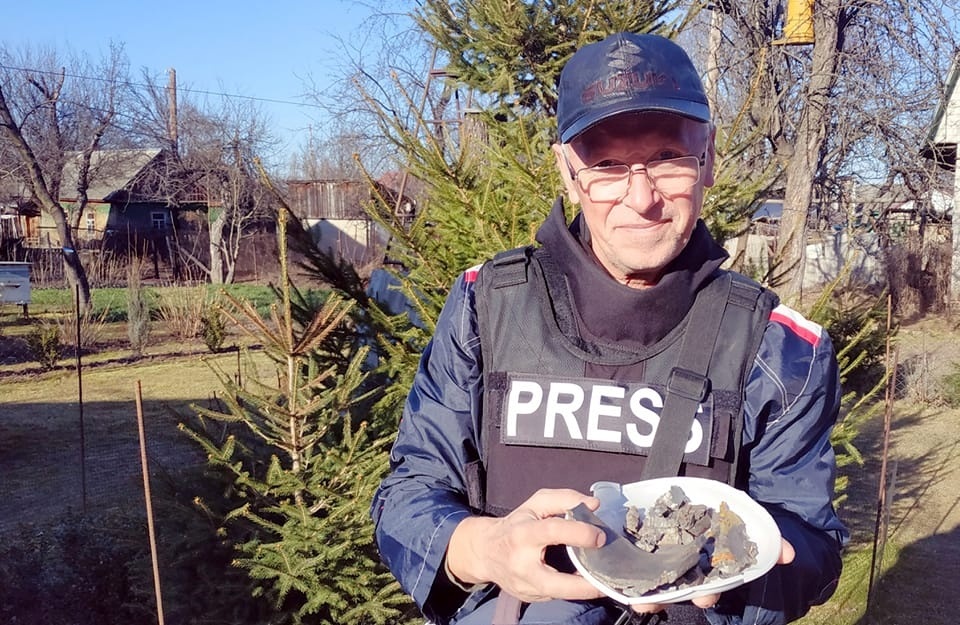 Владислав Савенок тримає осколки, які мешканець міста назбирав у своєму дворі. Бронежилет з написом "Press" журналіст отримав від колег 23 березня
